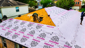 Roof underlayment San Antonio installation on a residential Texas home showing professional roofers applying a protective moisture barrier over roof decking before new shingles.